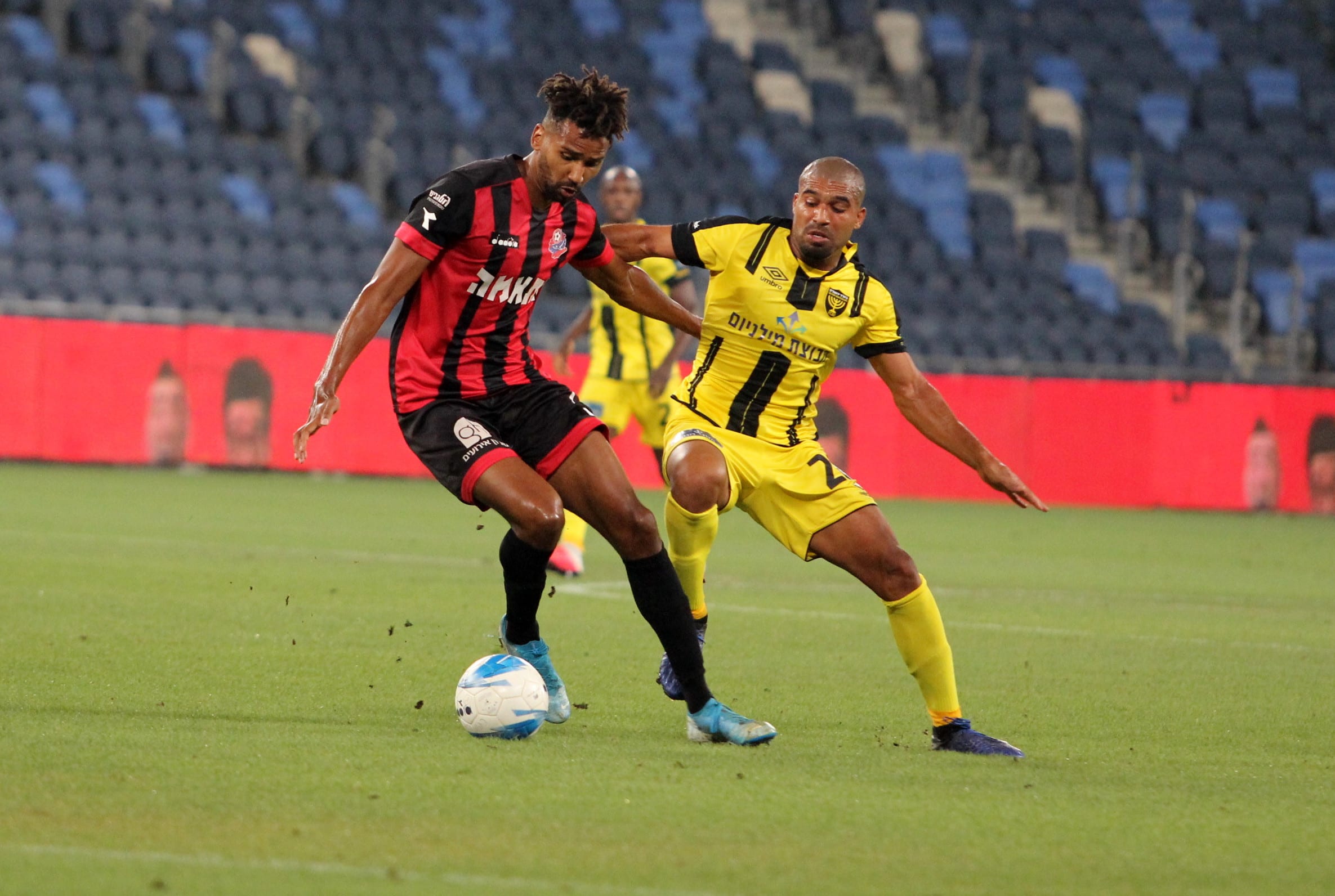 קווין טאפוקו שחקן הפועל חיפה לפני אורי מגבו שחקן בית"ר ירושלים