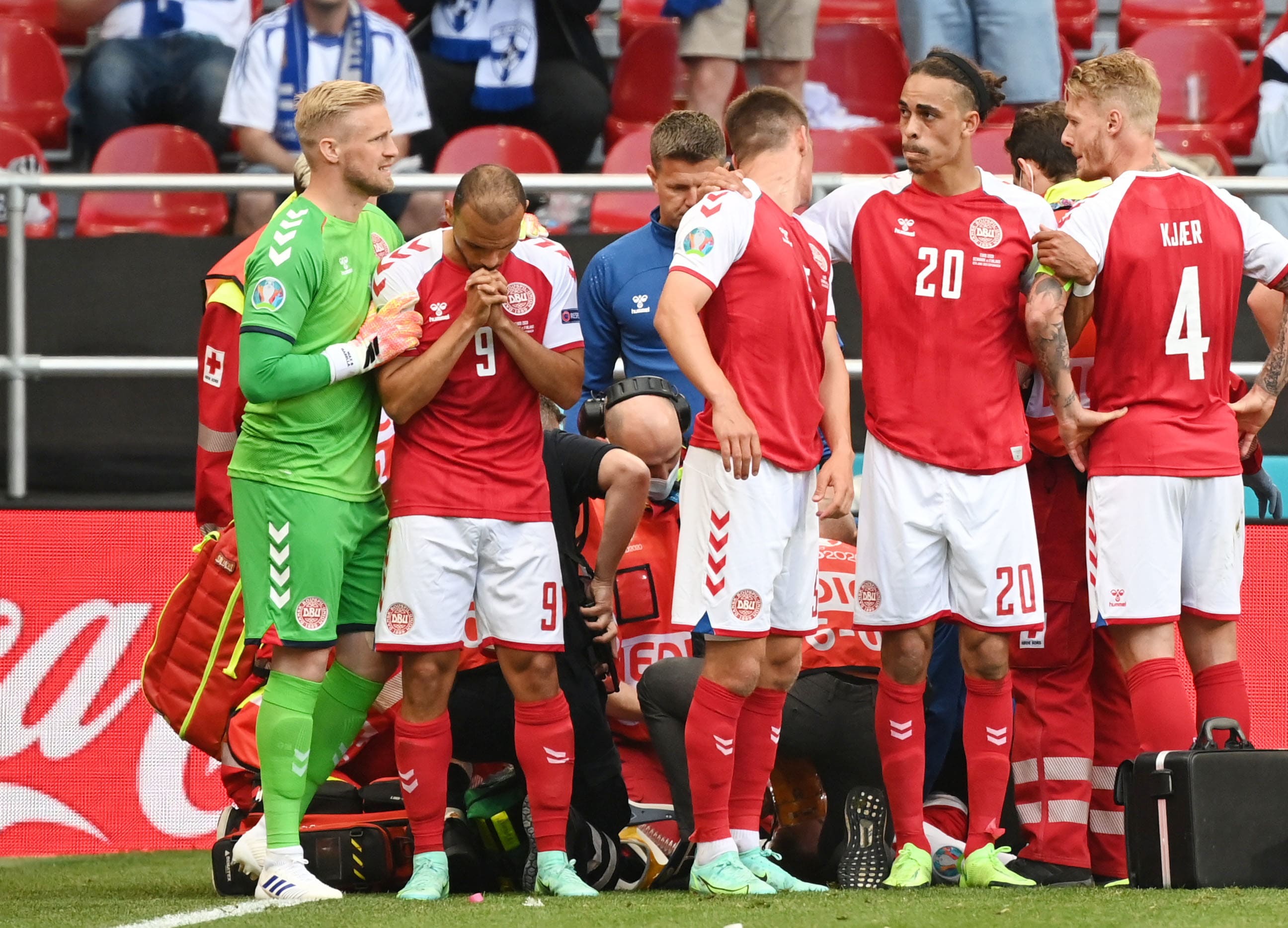 שחקני נבחרת דנמרק מרטין ברייתווייט, יוסוף פאולסן, קספר שמייכל עומדים סביב כריסטיאן אריקסן