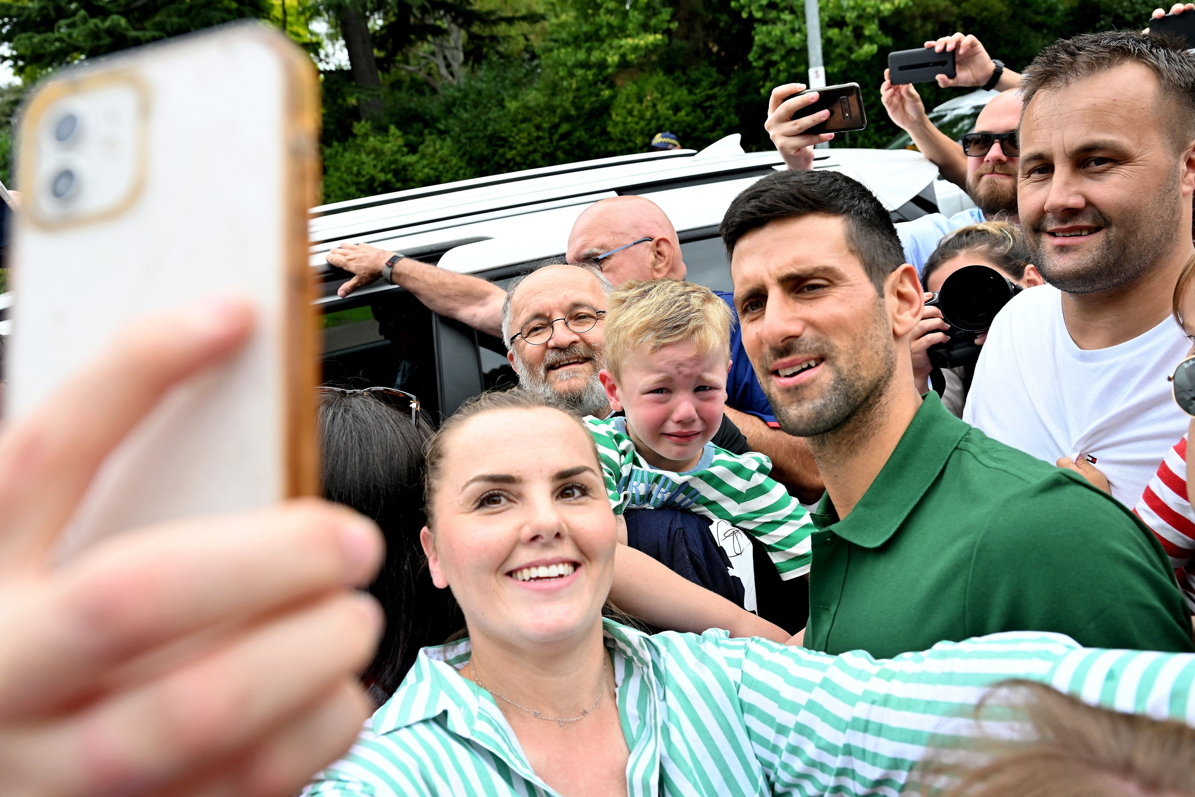 נובאק דג'וקוביץ' מצטלם עם מעריצים במלבורן, כולל ליד ילד בוכה