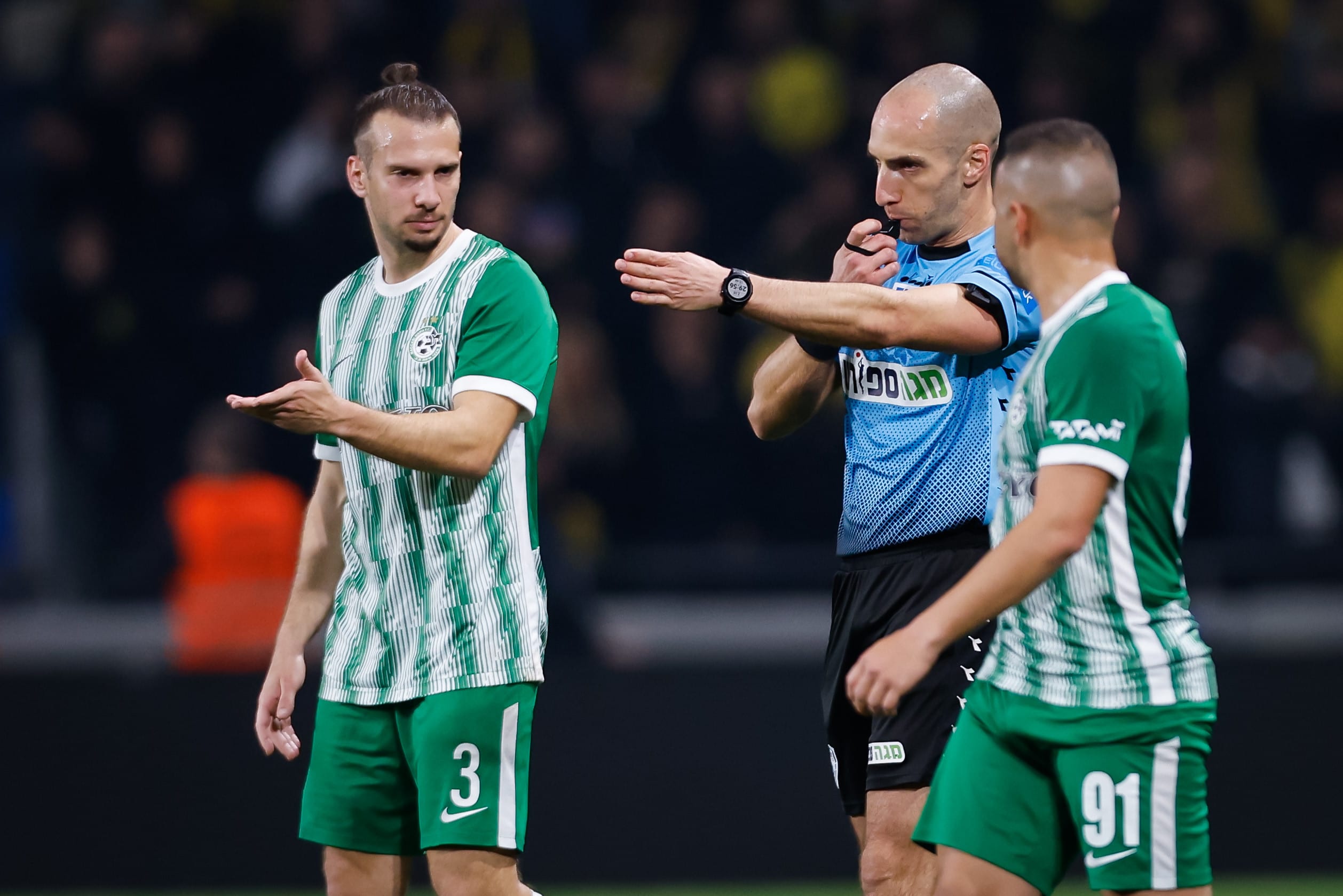 השופט גל לייבוביץ' מצביע על הנקודה הלבנה, לידו שון גולדברג שחקן מכבי חיפה