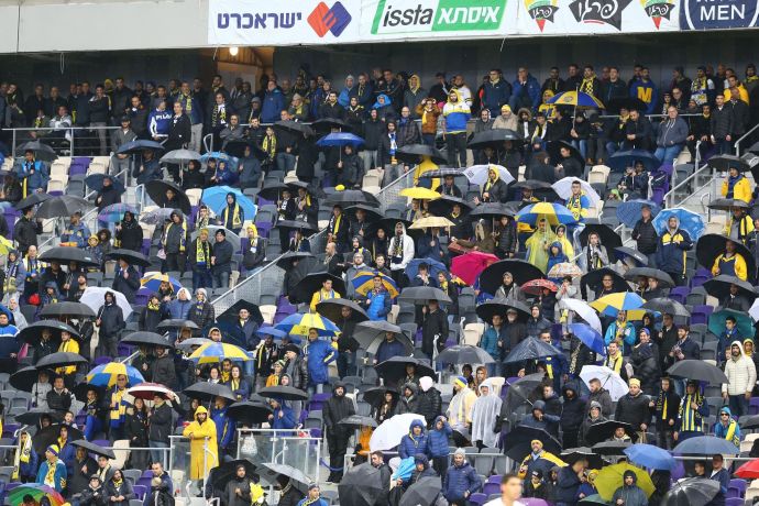 אוהדי מכבי תל אביב עם מטריות, גשם, אצטדיון בלומפילד
