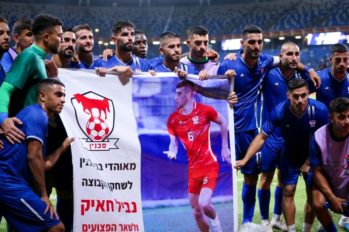 שחקני בני סכנין עם השלט לכבוד נביל חאיק