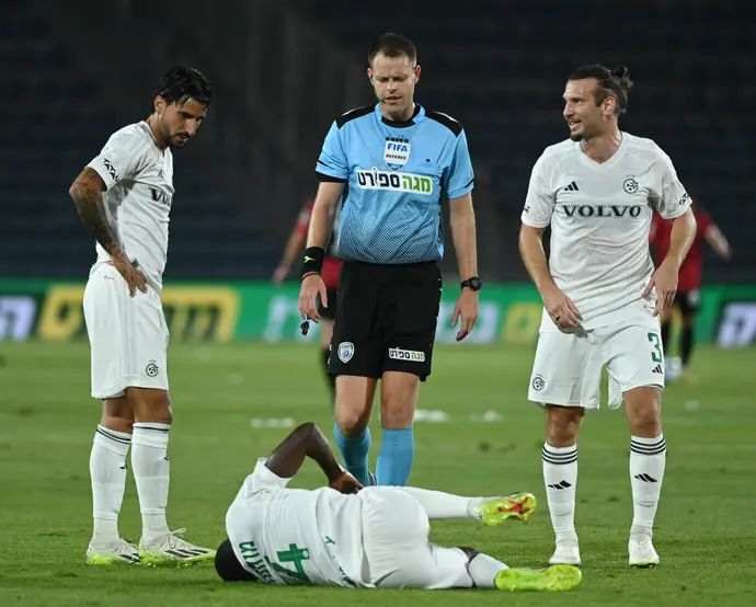 שון גולדברג, ליאור רפאלוב שחקני מכבי חיפה עם השופט יגאל פריד מעל עלי מוחמד הפצוע