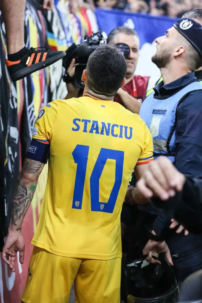 ניקולאה סטנצ'ו קפטן נבחרת רומניה מנסה לדבר עם האוהדים שהניפו שלט נגד קוסובו