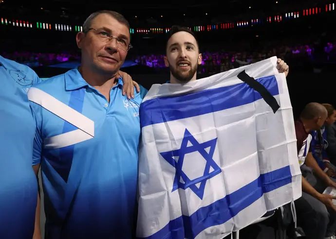 ארטיום דולגופיאט עם מאמנו סרגיי וייסבורג מניף דגל ישראל עם סרטים שחורים, אליפות העולם בהתעמלות 2023