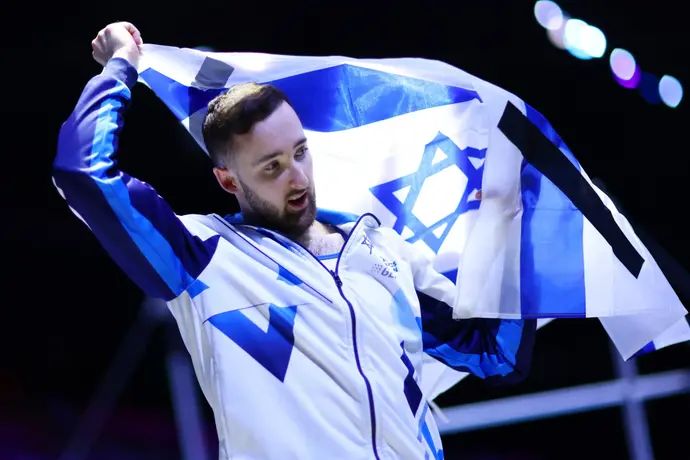 ארטיום דולגופיאט עם סרטים שחורים על דגל ישראל אחרי הזכייה שלו במדליית הזהב על תרגיל הקרקע באליפות העולם בהתעמלות