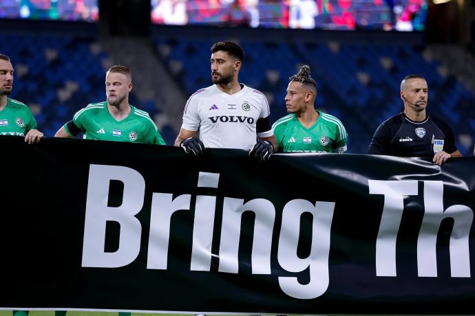 שחקני מכבי חיפה עם שלט הקורא להחזרת החטופים. צ'ארון שרי, דניאל סונדגרן לא מחזיקים