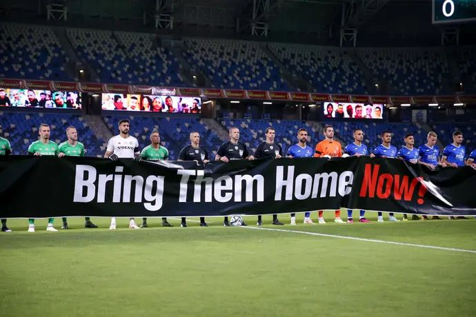 שחקני מכבי חיפה ושחקני הפועל פתח תקוה עם שלט הקורא להחזרת החטופים