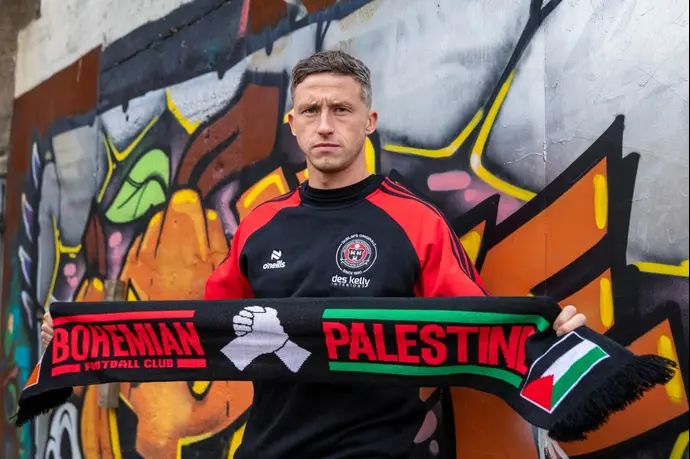 רוב קורנוול מוצג כשחקן בוהמיינס האירית, עם צעיף שנושא את שם הקבוצה ואת השם ודגל פלסטין