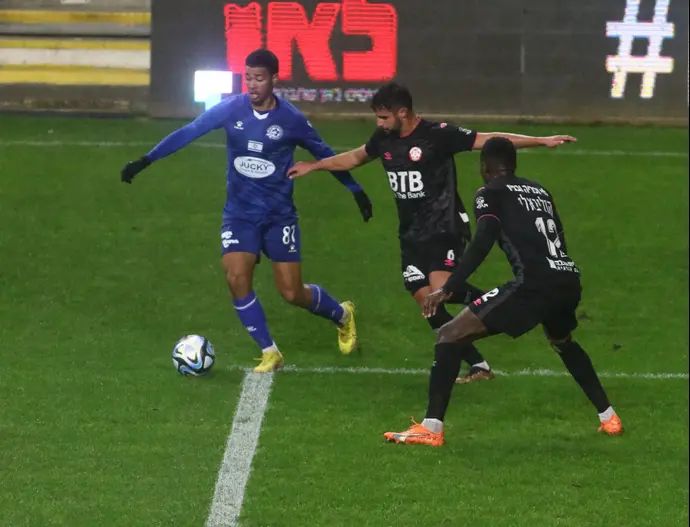 שחקן מכבי פתח תקוה עידן טוקלומטי מול שחקני הפועל חדרה: אביב לין, סולימאן קוליבאלי