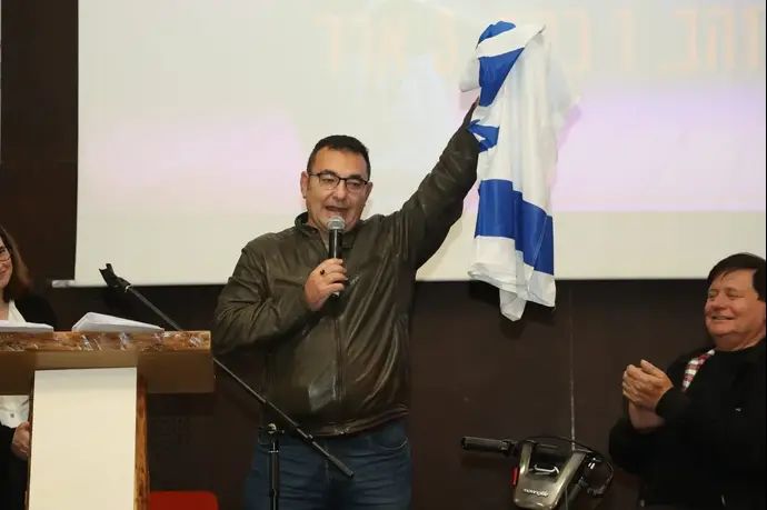 יעקב ביננסון מאמן נבחרת השחייה הפראלימפית מניף את דגל ישראל