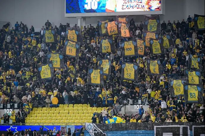 אוהדי מכבי תל אביב עם שלטים לזכר הנרצחים והנופלים במלחמה