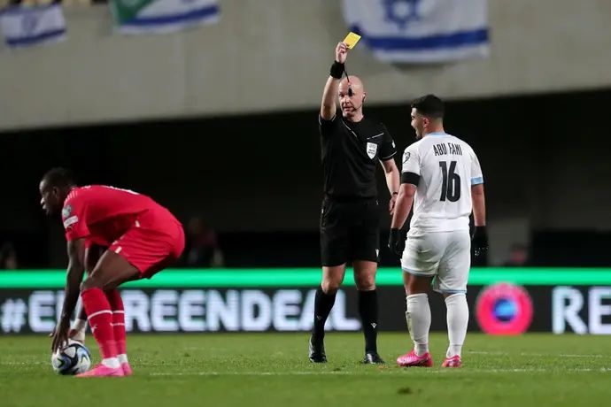 השופט אנתוני טיילור שולף כרטיס צהוב לשחקן נבחרת ישראל, מוחמד אבו פאני