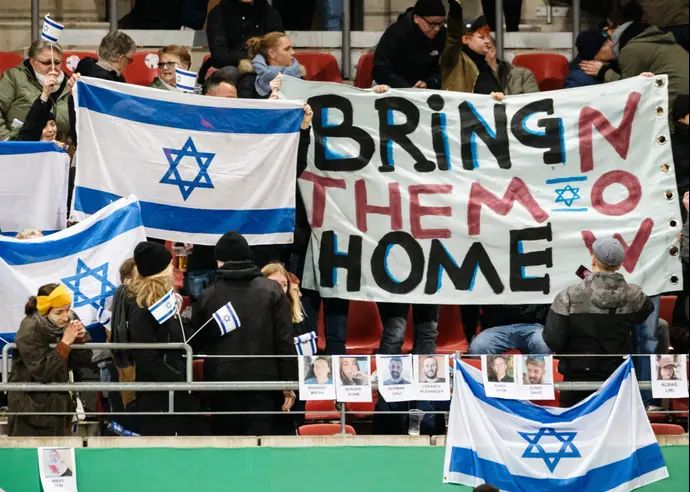 שלטים הקוראים להחזרת החטופים במשחק של נבחרת ישראל הצעירה בגרמניה
