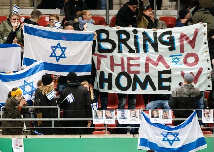 שלטים הקוראים להחזרת החטופים במשחק של נבחרת ישראל הצעירה בגרמניה