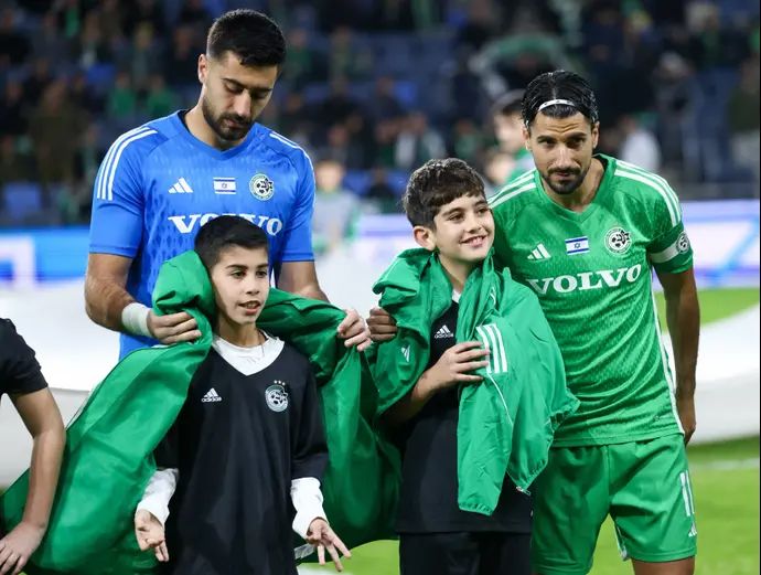 ליאור רפאלוב שחקן מכבי חיפה עם השוער שריף כיוף וילדים לפני המשחק