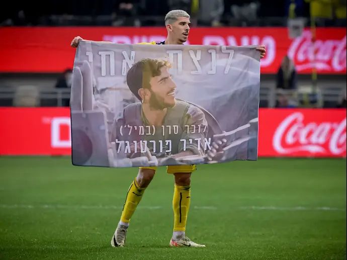 דור תורג'מן שחקן מכבי תל אביב עם דגל לזכרו של סרן במיל' אדיר פורטוגל ז