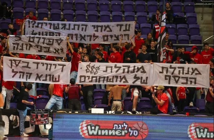 אוהדי הפועל ירושלים מניפים שלטים נגד מנהלת הליגה בכדורסל