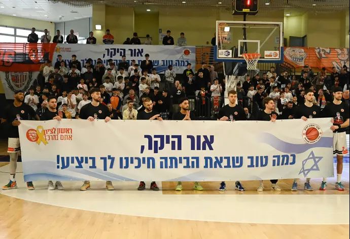 שחקני מכבי ראשון לציון עם שלט לחזרתו של אור לוי