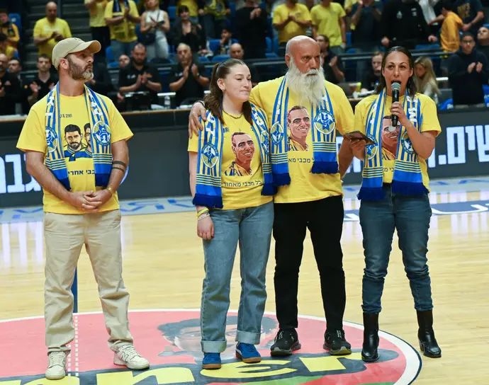 משפחות החטופים גיל וזיו ברמן ועומרי מירן על הפרקט לפני המשחק של מכבי תל אביב