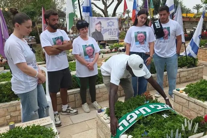 עלי מוחמד בבית הקברות עם משפחתו של אוהד הקבוצה, בני וייס ז"ל, שנפל בקרב