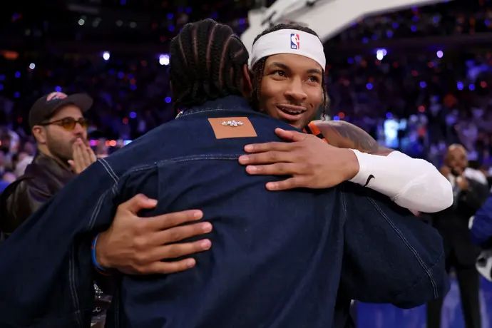 שחקן ניו יורק ניקס מיילס מקברייד מחבק את את כוכב הפוטבול סטפון דיגס על הפרקט במדיסון סקוור גארדן