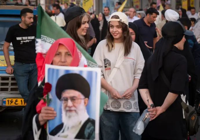 אישה מחזיקה כרזה של המנהיג העליון עלי חמינאי בעצרת בטהראן, איראן, 24 ביוני 2025