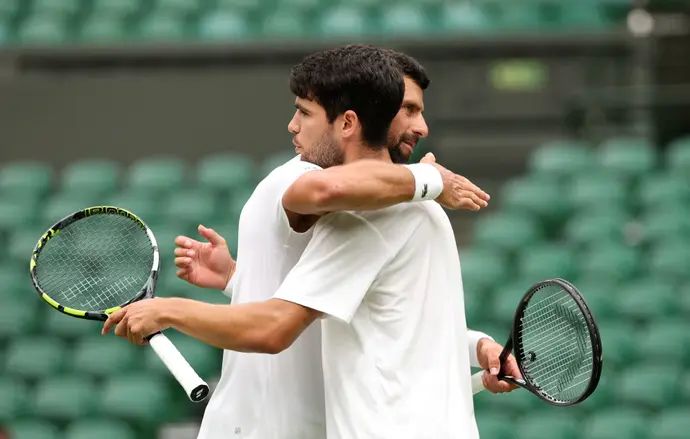 קרלוס אלקראס טניסאי ספרדי עם נובאק ג'וקוביץ' טניסאי סרבי לפני אימון משותף במגרש המרכזי של ווימבלדון