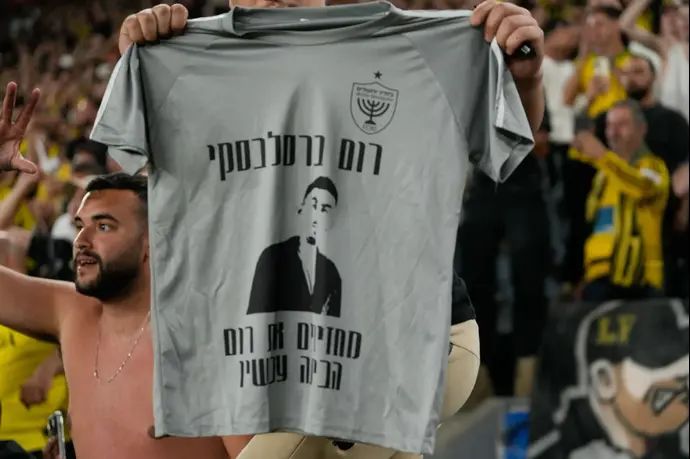 אוהד של בית"ר ירושלים עם חולצה הקוראת להחזרת החטוף רום ברסלבסקי