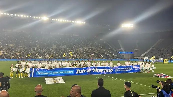 שחקני בית"ר ירושלים עם שלט של ארגון "לתת"