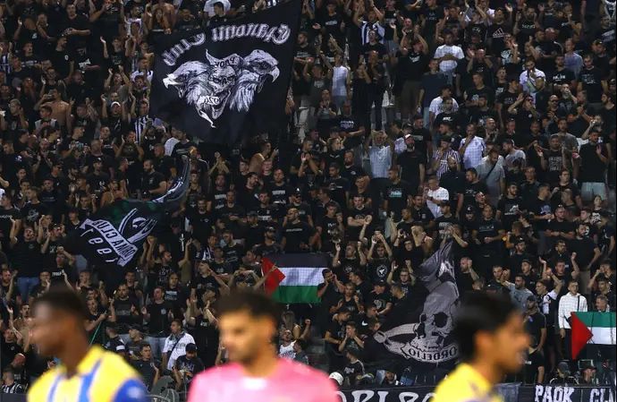 שחקני מכבי תל אביב על רקע דגלי פלסטין לפני המשחק מול פאוק סלוניקי