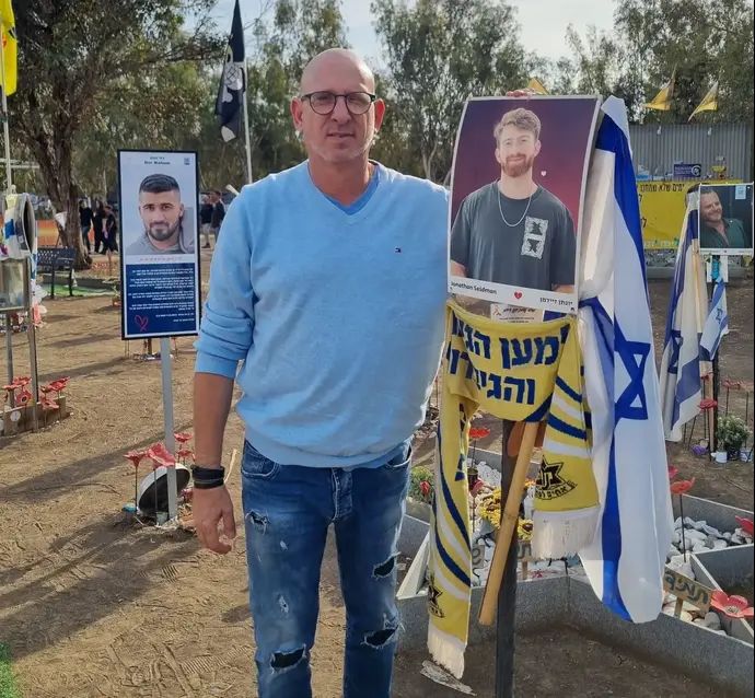 יוסי רול לצד תמונת אחיינו, יונתן זיידמן ז"ל, שנרצח ב-7 באוקטובר 2023