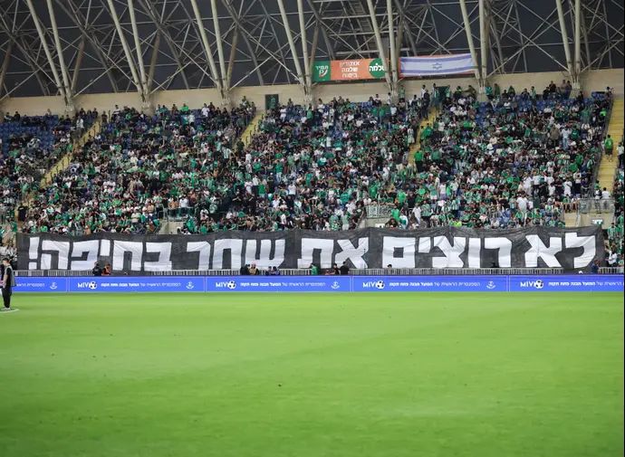 אוהדי מכבי חיפה עם שלט מחאה נגד הבעלים יעקב שחר