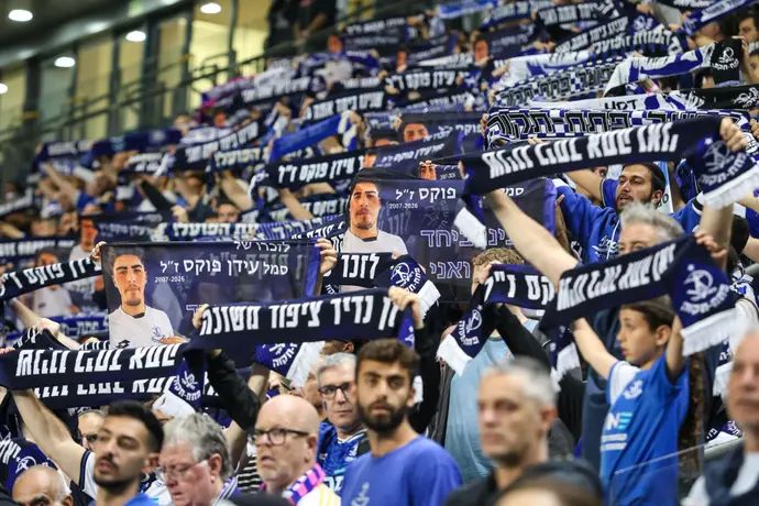 אוהדי הפועל פתח תקוה עם צעיפים לזכר סמל עידן פוקס ז"ל, אוהד הקבוצה שנפל בלבנון