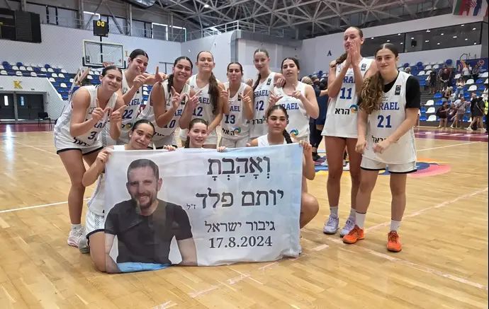 נבחרת הקדטיות לאחר הניצחון על רומניה עם שלט לזכרו של יותם פלד, קרוב משפחה של מנהלת הנבחרת, לילך וייס רוזנברג